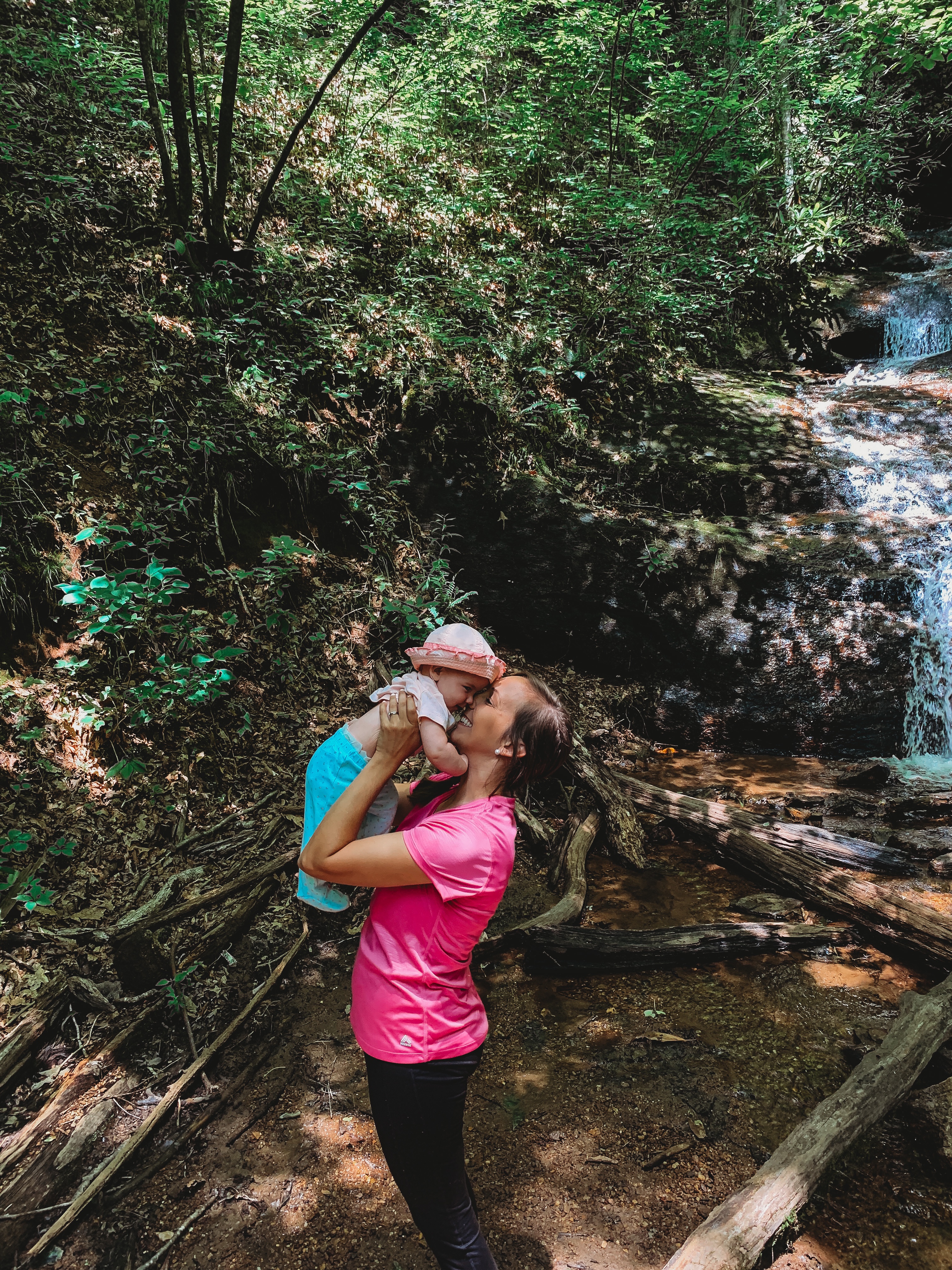 mom holding baby by waterfall