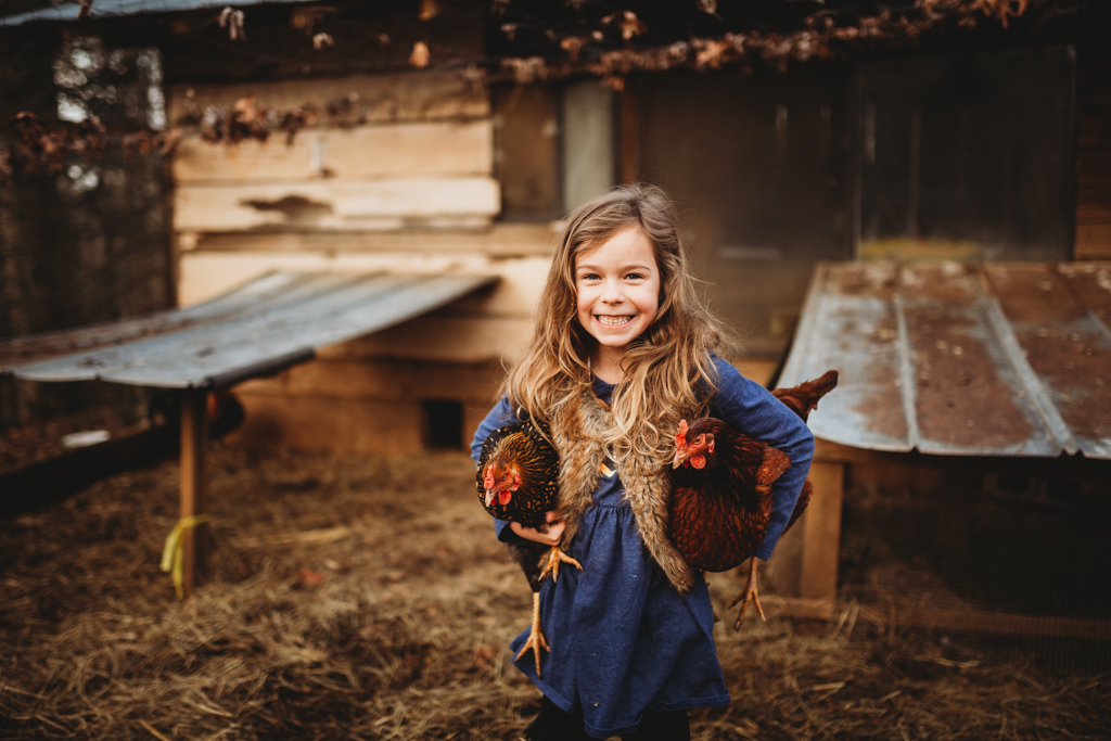 girl holding two chickens on mini farm 